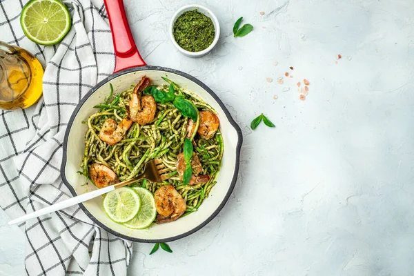 stock image Zucchini spaghetti with pesto sauce and grilled shrimp skewers in pan. keto low carb diet. banner, menu, recipe place for text, top view.