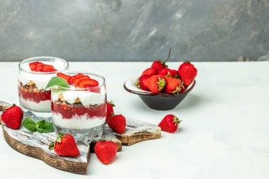 Taze meyve, yoğurt ve beyaz masada granola, cam kavanoz. Sağlıklı kahvaltı. Uzun afiş biçimi. en üstteki görünüm.