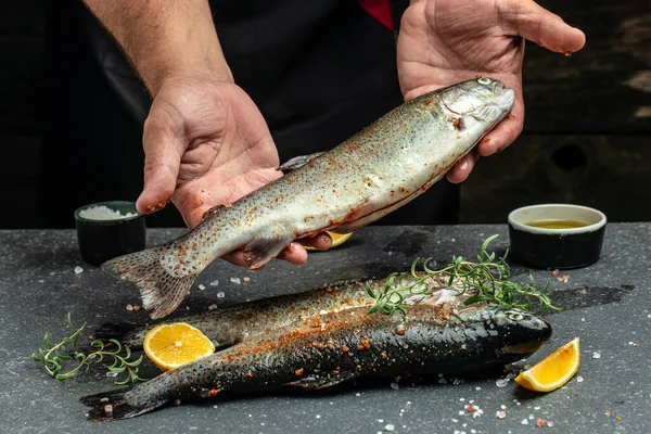 Male hands holding rainbow trout with spices, Fish dish cooking, Culinary, cooking, bakery concept,