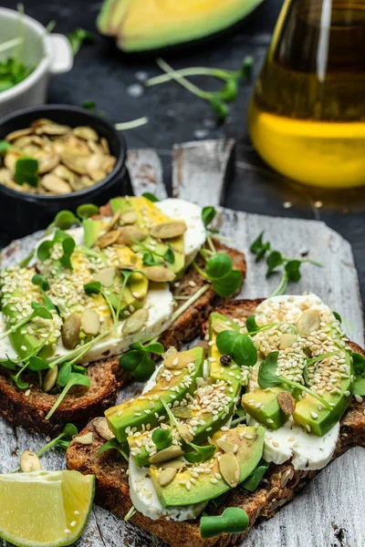 avocado toasts with cheese, pumpkin, nut and sesame. Healthy fats, clean eating for weight loss.