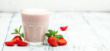 Meyveli smoothie. Çilekli smoothie ya da meyveli milkshake ve beyaz arka planda cam kavanozda yoğurt. Sağlıklı vejetaryen içeceği. Uzun afiş biçimi. en üstteki görünüm.