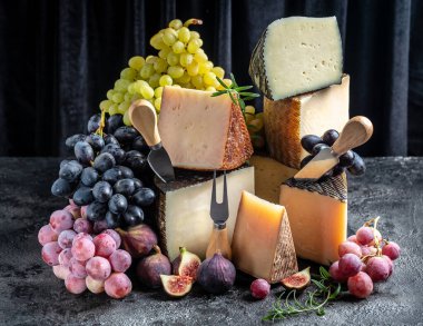 Üzüm ve incirli farklı peynir çeşitleri. Peynir arka planı. Geleneksel İspanyol, Fransız, İtalyan peyniri parçaları.