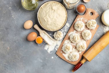 Tahtada et olan çiğ Khinkali. Yarı bitmiş hamur köfteleri karanlık bir arka planda khinkali pişiriyor. Gürcü böreği. metin için yer, üst görünüm.