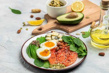 Keto diyet yemeği, somon, avokado, peynir, yumurta, ıspanak ve fındık. Ketojenik düşük karbonhidrat diyet konsepti. Sağlıklı yiyecekler seçimi için malzemeler, metin için yer, üst görünüm,