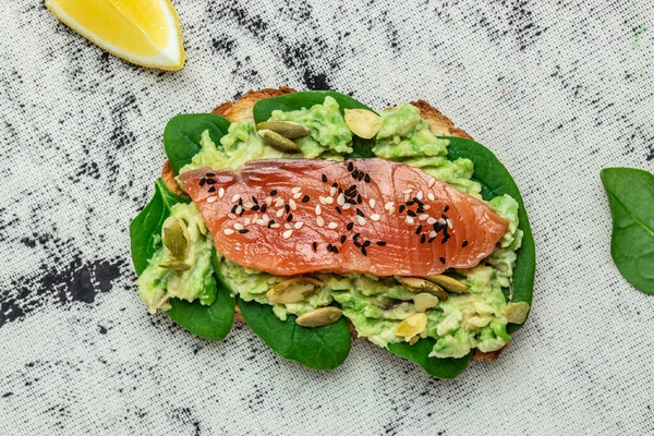 Avokadoo, somon ve ıspanak, fındık ve ayçekirdeği ile tost. Sağlıklı, temiz yemek. Vejetaryen ya da glütensiz diyet. Üst görünüm, boşluk kopyala.