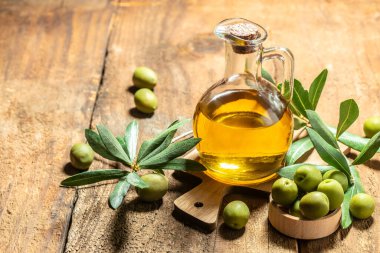 Siyah ve yeşil zeytinli ve yapraklı şişelerde zeytin yağı. Ahşap arka planda ekstra saf zeytinyağı kavanozları. metin için yer.