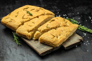 Foccacia ekmeği. Koyu bir arka planda zeytinyağı ve bitkiler. afiş, menü, metin için tarif yeri, üst görünüm.