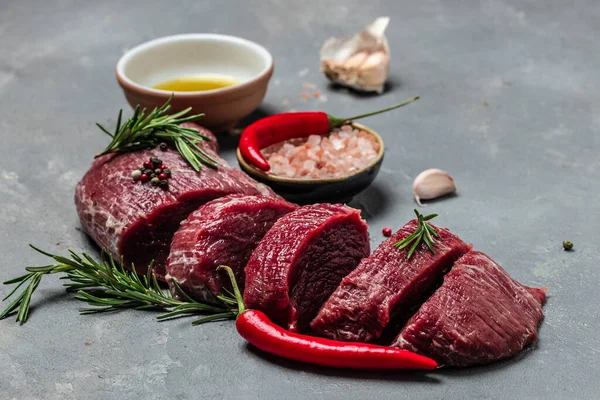 Beef medallions with rosemary and spices, Raw beef meat steak Tenderloin fillet on a dark background. banner, menu, recipe place for text, top view.