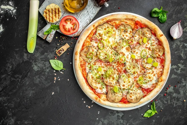 vegan pizza with eggplant, tomatoes and leeks on a dark background, banner, menu, recipe place for text, top view.