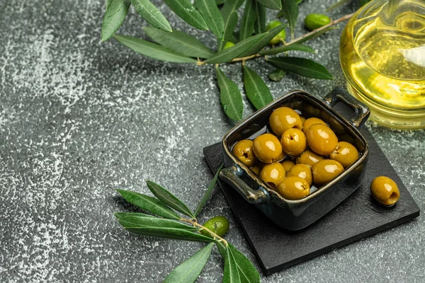 Green olives with feta cheese and young olives branch on dark background. top view. place for text.