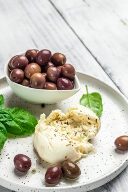 Beyaz tabakta fesleğenli ve zeytinyağlı kremalı İtalyan Burrata peyniri. İtalyan Akdeniz mutfağı. dikey görüntü. Üst Manzara. metin için yer,