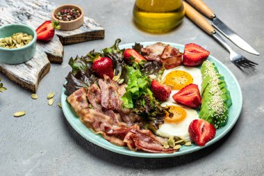 Yağda yumurta, pastırma, avokado, çilek ve hafif arkaplanda taze salata. Ketojenik diyet yiyecekler, sağlıklı yemek konsepti, uzun afiş formatı. en üstteki görünüm.