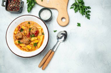 Etli, patatesli, soğanlı güveç, domates soslu kabak, sarımsak ve otlar beyaz bir kasede, yazı için yer, üst görünüm,