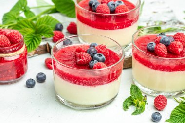 Hafif arka planda ahududu reçelli ahududu panna cotta. Küçük kavanozlarda krema soslu böğürtlen tatlısı. metin için yer.