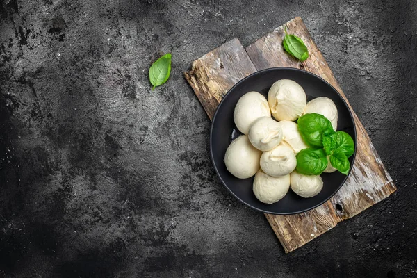 Peynir koleksiyonu, koyu arkaplanda taze fesleğen yapraklı beyaz İtalyan peynirli mozzarella topları. Uzun afiş biçimi. en üstteki görünüm.