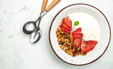 Bir kase ev yapımı granola, taze çilek, chia tohumu ve bal. Lezzetli kahvaltı ya da atıştırmalık. afiş, menü, metin için tarif yeri, üst görünüm.