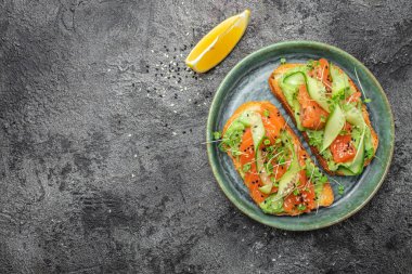 İki tost, tuzlanmış somon, avokado ve taze yeşillikler. Süper yiyecek konsepti. Sağlıklı, temiz yemek. Vejetaryen ya da glütensiz diyet. en üstteki görünüm.