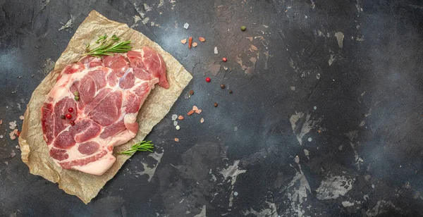 stock image pork meat steaks with rosemary and pepper on a dark background. Long banner format. top view.