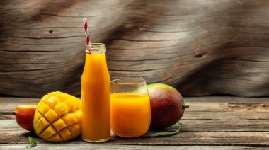 Bardakta mango suyu var. Tahta arka planda taze tropikal meyve. Uzun pankart biçimi.