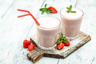 Çilekli smoothie ya da meyveli milkshake ve beyaz beton arka planda cam kavanozda yoğurt. Sağlıklı vejetaryen içeceği. metin için yer, üst görünüm,