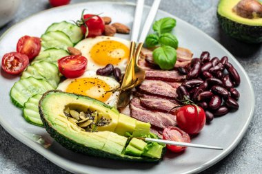 Keto breakfast with avocado, fried eggs, bacon, and beans. paleo keto breakfast diet lunch. Healthy nutritious paleo keto breakfast concept. Food recipe background. Close up, clipart