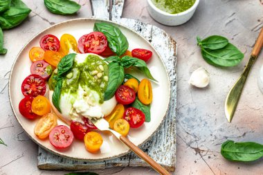 Salad burrata cheese tomatoes and green pesto. Delicious balanced food concept. superfood concept. Healthy, clean eating. Vegan or gluten free diet. top view.