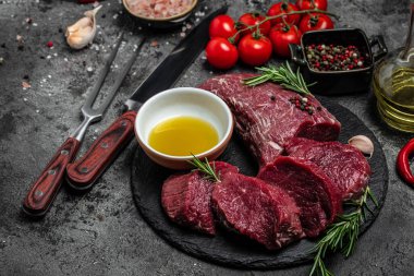 Biberiye ve baharatlı sığır eti madalyonları koyu arkaplanda çiğ biftek fileto. afiş, menü, metin için tarif yeri, üst görünüm.