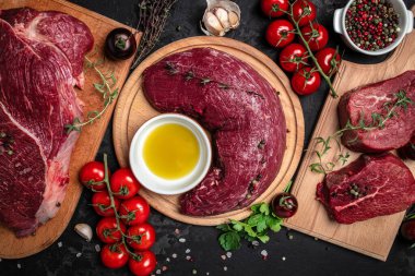 Biberiyeli sığır filetosu ve koyu arkaplanda baharatlar. Pişirmeye hazır taze biftek hazırlıyorum. en üstteki görünüm.