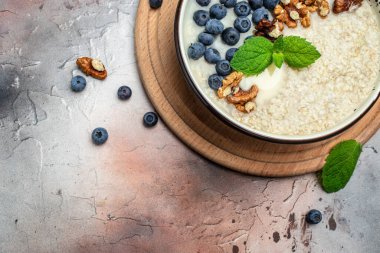 Kahvaltı için yulaf lapası, olgun yaban mersini, fındık ve bal dolu kaseleri kapat..