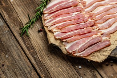 Çiğ tütsülenmiş pastırma dilimleri ve ahşap tahtada biberiye. afiş, menü, metin için tarif yeri, üst görünüm.