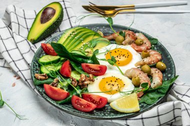 Karides, karides, yağda yumurta, taze salata, domates, salatalık ve avokado. Ketogenik diyet kahvaltısı. Keto, paleo yemeği. Üst görünüm.