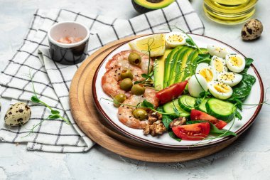 Ketojenik kahvaltı. Az karbonhidratlı karides, karides, bıldırcın yumurtası, taze salata, domates, salatalık ve avokado. Keto diyeti. Üst görünüm,
