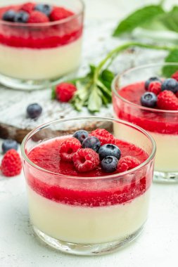 İtalyan tatlısı. Hafif arka planda ahududu reçelli ahududu panna cotta. Küçük kavanozlarda krema soslu dut tatlısı..