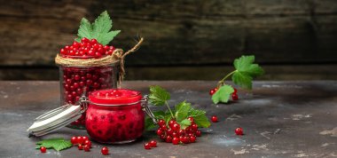 Ev yapımı meyveli reçel. Kırmızı fonda frenk üzümü reçeli olan cam kavanoz. Uzun afiş biçimi. en üstteki görünüm.