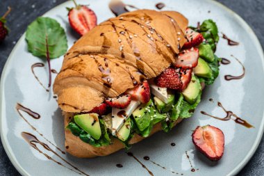 Avokado, çilek, peynirli peynirli sandviç, tohumlu buğday ekmekli taze salata. Sağlıklı beslenme konsepti. afiş, menü, tarif, üst görünüm.