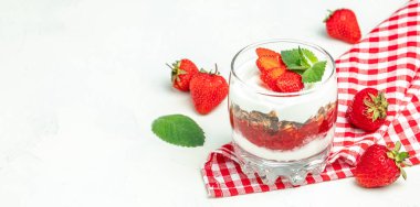 Taze meyve, yoğurt ve beyaz masada granola, cam kavanoz. Sağlıklı kahvaltı. Uzun afiş biçimi. en üstteki görünüm.