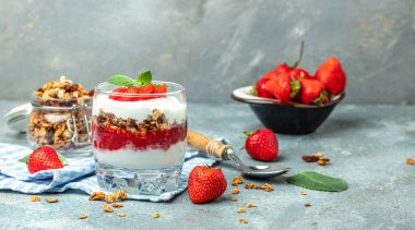 Taze meyve, yoğurt ve beyaz masada granola, cam kavanoz. Sağlıklı kahvaltı. Uzun afiş biçimi. en üstteki görünüm.