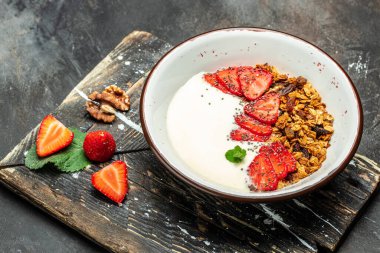 Yoğurtlu granola, taze çilek, chia tohumu ve bal, koyu arkaplanda. Lezzetli dengeli gıda konsepti. afiş, menü, metin için tarif yeri, üst görünüm.