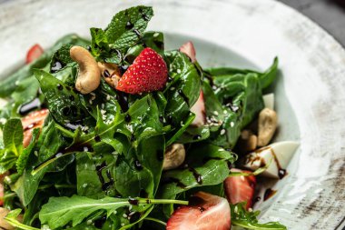 Ispanaklı çilek salatası, fındık, peynir, gri taşlı arka planda taze vejetaryen salatası, afiş, menü, yazı için tarif yeri, üst görünüm,