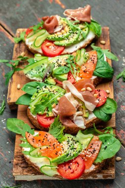 Krem peynirli sandviç seti, prosciutto, somon, avokado ve taze yeşillik. Keto, ketojenik diyet, düşük karbonhidrat, yüksek yağ, sağlıklı yiyecekler. en üstteki görünüm.