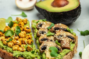 Hafif bir arka planda nohut ve mantarlı sağlıklı avokado tostları, vejetaryen yemekleri. Üst Manzara. metin için yer.