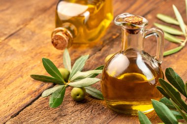 Zeytinyağlı yeşil zeytin. Ahşap arka planda ekstra saf zeytinyağı kavanozları. metin için yer.