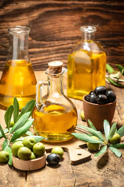 olives and oil. extra virgin olive oil jars on a wooden background. vertical image. place for text.