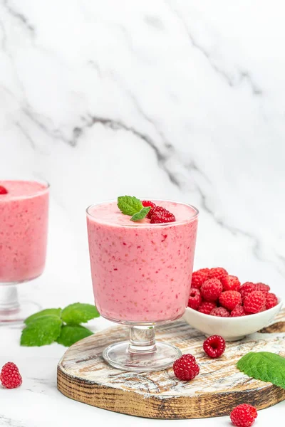 Yogurt smoothie with raspberries in glass on white marble table. weight loss concept. vertical image. place for text.