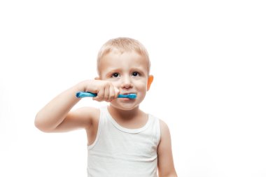 Çocuk beyaz arka planda dişlerini fırçalar. Diş fırçalı mutlu bir erkek bebek. Diş hijyeni.