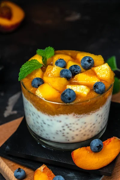 yogurt dessert with peaches blueberry chia on a dark background. Natural detox, fruit dessert, healthy dieting concept.