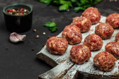 Kesme tahtasında baharatlı taze çiğ et köfteleri koyu arkaplan, pankart, menü, metin için tarif yeri, üst görünüm.