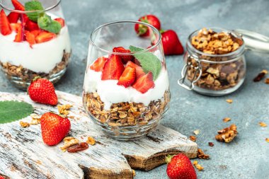 Taze meyveli parfe, Yunan yoğurdu, yulaf ezmesi, bal ve nane yaprakları ahşap bir tahtanın üzerinde cam kavanozda. Glütensiz diyet, sağlıklı kahvaltı. metin için yer, üst görünüm,