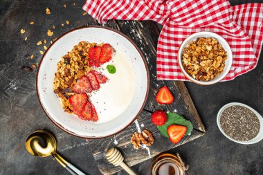 Yoğurtlu granola, taze çilek, chia tohumu ve bal, koyu arkaplanda. Lezzetli dengeli gıda konsepti. afiş, menü, metin için tarif yeri, üst görünüm.