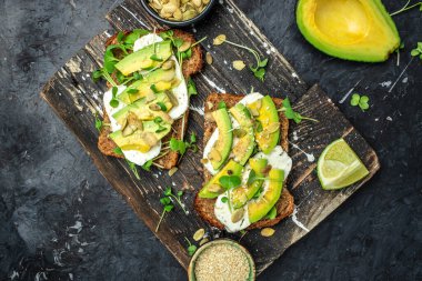 Sağlıklı avokado tostları, çavdar ekmeği dilimlenmiş avokado, peynir, balkabağı, fındık ve susamlı kahvaltı ya da öğle yemeği. Vejetaryen yemeği. Vejetaryen menüsü. Yemek tarifi.